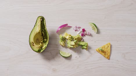 Video-of-tortilla-chip,-awocado,-onion-and-lime-on-a-wooden-surface
