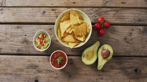 Video-of-tortilla-chips,-guacamole-and-salsa-dip-on-a-wooden-surface