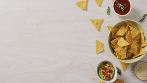 Video-of-tortilla-chips,-guacamole-and-salsa-dip-on-a-wooden-surface