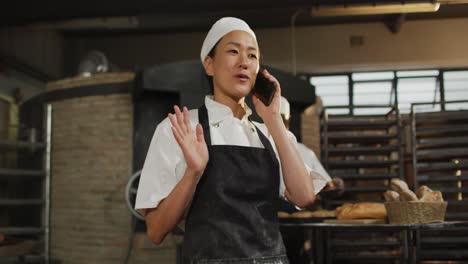 Animation-of-happy-asian-female-baker-having-call