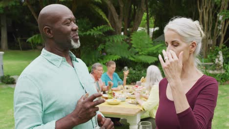Animation-of-diverse-happy-senior-female-and-male-friends-talking-in-garden