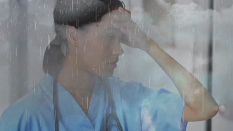 Animation-of-clouds-and-rain-over-sad-biracial-female-nurse-in-hospital