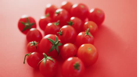 Video-of-close-up-of-fresh-red-cherry-tomatoes-on-pink-background