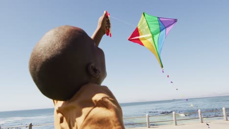 Video-Eines-Glücklichen-Afroamerikanischen-Jungen,-Der-Spaß-Mit-Drachen-Hat-Und-Am-Strand-Läuft