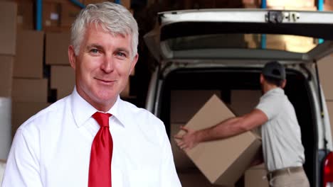 Delivery-driver-packing-his-van-with-manager-smiling-at-camera