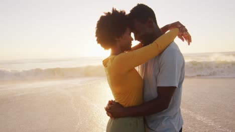 Lächelndes-Afroamerikanisches-Paar,-Das-Sich-Am-Sonnigen-Strand-Im-Wasser-Umarmt