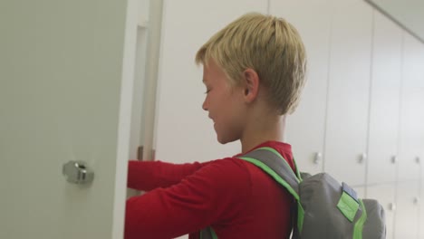 Video-of-caucasian-boy-closing-locker-and-smiling-at-school