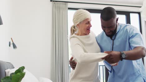 Video-of-happy-african-american-male-doctor-taking-care-of-caucasian-senior-woman