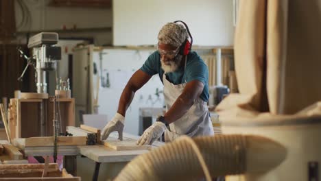 African-american-male-carpenter-using-table-saw-for-cutting-wood-at-a-carpentry-shop
