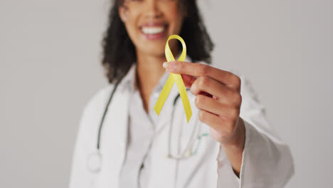 Video-of-smiling-biracial-female-doctor-holding-yellow-bladder-cancer-ribbon