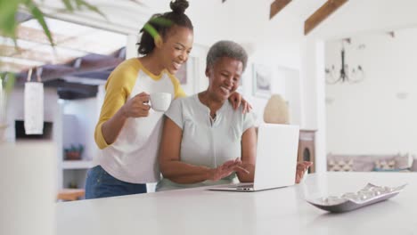 Afroamerikanische-Mutter-Und-Tochter-Lächeln,-Während-Sie-Zu-Hause-Gemeinsam-Einen-Laptop-Benutzen