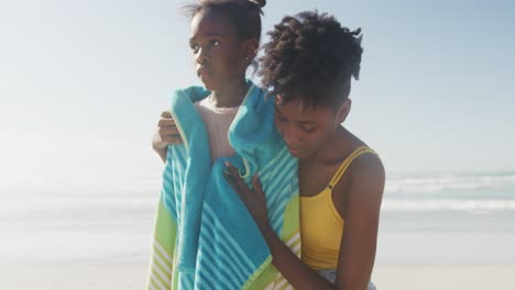 Afroamerikanische-Mutter-Trocknet-Ihre-Tochter-Mit-Einem-Handtuch-Am-Strand