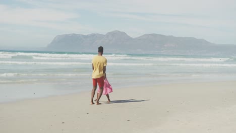African-american-father-and-daughter-holding-hands-jumping-at-the-beach
