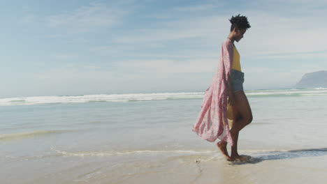Feliz-Mujer-Afroamericana-Caminando-Con-Sombrero-En-La-Playa-Soleada