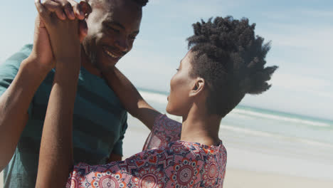 Glückliches-Afroamerikanisches-Paar,-Das-Am-Sonnigen-Strand-Tanzt-Und-Händchen-Hält