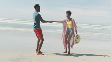 Glückliches-Afroamerikanisches-Paar,-Das-Am-Sonnigen-Strand-Händchen-Hält