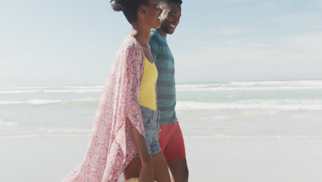 Glückliches-Afroamerikanisches-Paar,-Das-Am-Sonnigen-Strand-Händchen-Hält