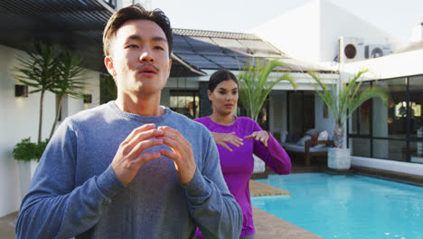 Video-of-relaxed-diverse-couple-exercising-tai-chi-in-garden