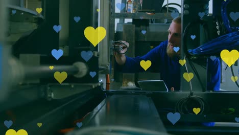 Animation-of-falling-blue-and-yellow-hearts-over-caucasian-factory-worker