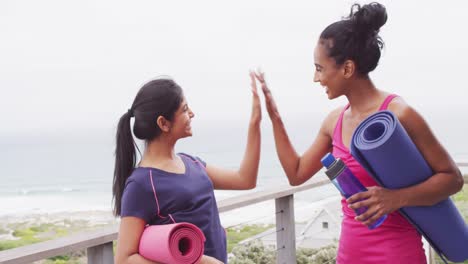 Video-of-happy-diverse-female-friends-holding-yoga-mats-and-clapping-hands