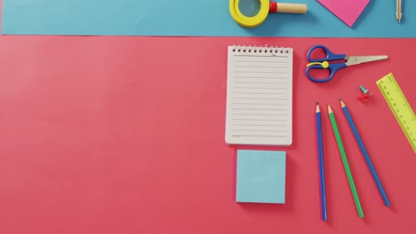 Video-of-notebook-with-copy-space-and-school-items-on-pink-and-blue-background