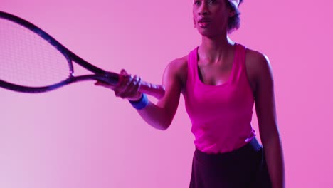 Video-Einer-Fokussierten-Afroamerikanischen-Tennisspielerin,-Die-Den-Ball-Auf-Neonpinken-Blitzen-Schlägt