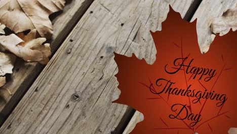 Animation-of-happy-thanksgiving-day-text-over-autumn-leaf-on-wooden-boards-background