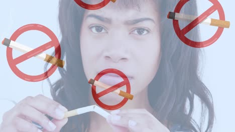 Animation-of-lit-cigarettes-with-no-smoking-signs-over-biracial-woman-breaking-cigarette
