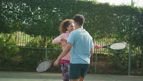 Video-of-happy-biracial-couple-playing-tennis-on-the-court