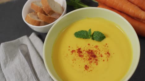 Video-of-cream-vegetable-soup-in-bowl-on-grey-table-with-carrots