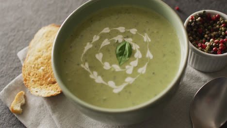 Video-of-green-peas-soup-and-ingredients-lying-on-grey-surface