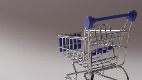 Empty-blue-shopping-trolley-on-grey-background