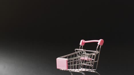 Empty-shopping-trolley-on-seamless,-lit-black-background-with-copy-space