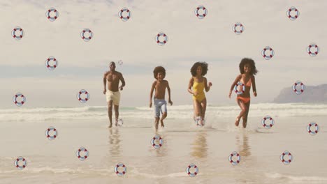 Animation-of-life-buoys-over-happy-african-american-parents-and-children-running-from-sea-to-beach