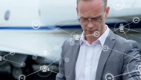 Animation-of-network-of-digital-icons-over-caucasian-businessman-checking-time-at-an-airport