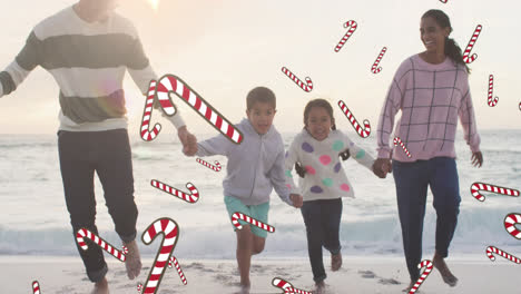 Animation-of-candy-canes-over-biracial-family-at-beach