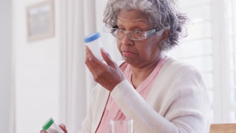 Ältere-Afroamerikanische-Frau-Sitzt-Am-Tisch-Und-Nimmt-Pillen
