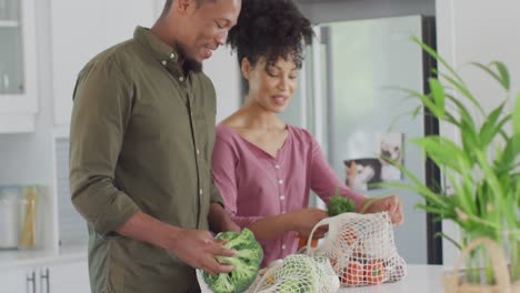 Glückliches-Afroamerikanisches-Paar-Mit-Säcken-Voller-Gemüse-In-Der-Küche