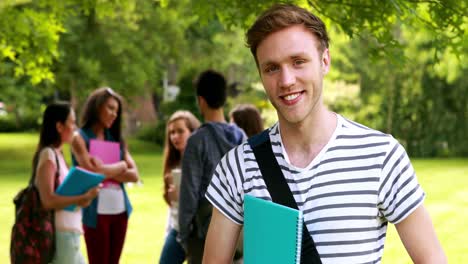 Smiling-student-posing-and-classmates-speaking-behind-him