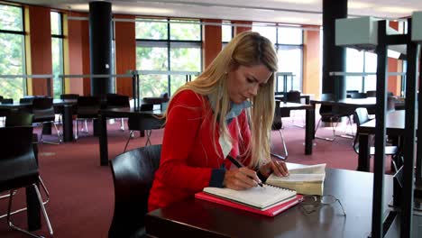 Mature-student-with-reading-glasses-studying-at-library-desk