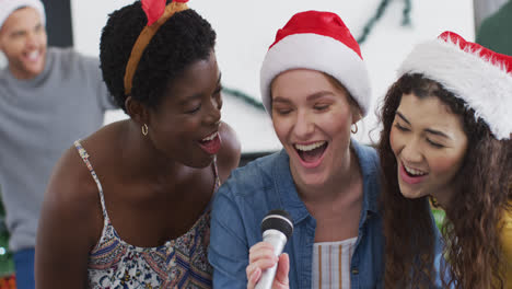 Happy-group-of-diverse-friends-singing-karaoke-at-christmas-party