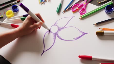 Video-Einer-Handgezeichneten-Blume-Mit-Lila-Stift-Auf-Papier,-Mit-Auf-Der-Tischplatte-Angeordneten-Kunstmaterialien