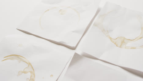 Video-close-up-of-four-pieces-of-paper-with-coffee-mug-stains-on-white-background