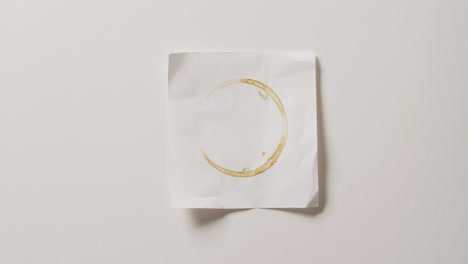 Video-close-up-of-piece-of-paper-with-coffee-mug-stain-on-white-background