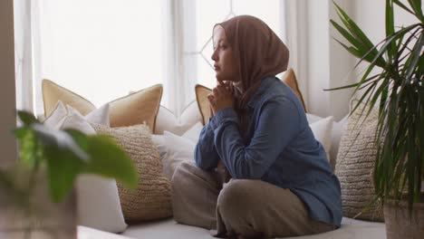 Video-De-Una-Mujer-Birracial-Pensativa-Con-Hijab-Sentada-En-Un-Sofá-En-La-Sala-De-Estar-De-Casa