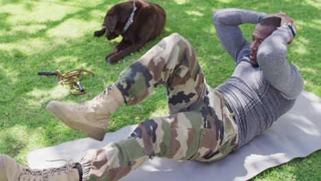 African-american-male-soldier-exercising-and-doing-sit-ups-with-dog-in-garden