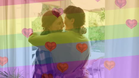 Animation-Von-Herz-Emojis-Und-Regenbogenfahne-über-Einem-Kaukasischen-Weiblichen-Paar,-Das-Sich-Umarmt