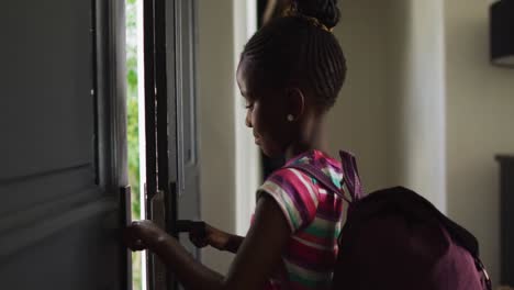 Video-Eines-Afroamerikanischen-Mädchens-Mit-Schultasche,-Das-Die-Haustür-öffnet-Und-Das-Haus-Zur-Schule-Verlässt