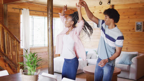 Happy-african-american-couple-dancing-together-in-log-cabin,-slow-motion
