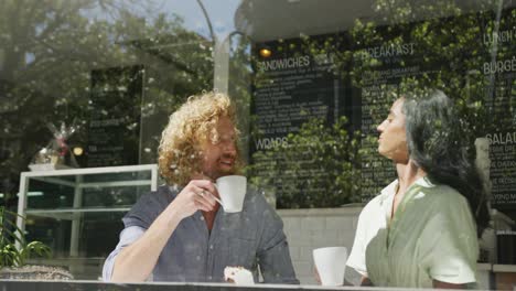 Happy-diverse-couple-drinking-coffee-and-talking-in-cafe